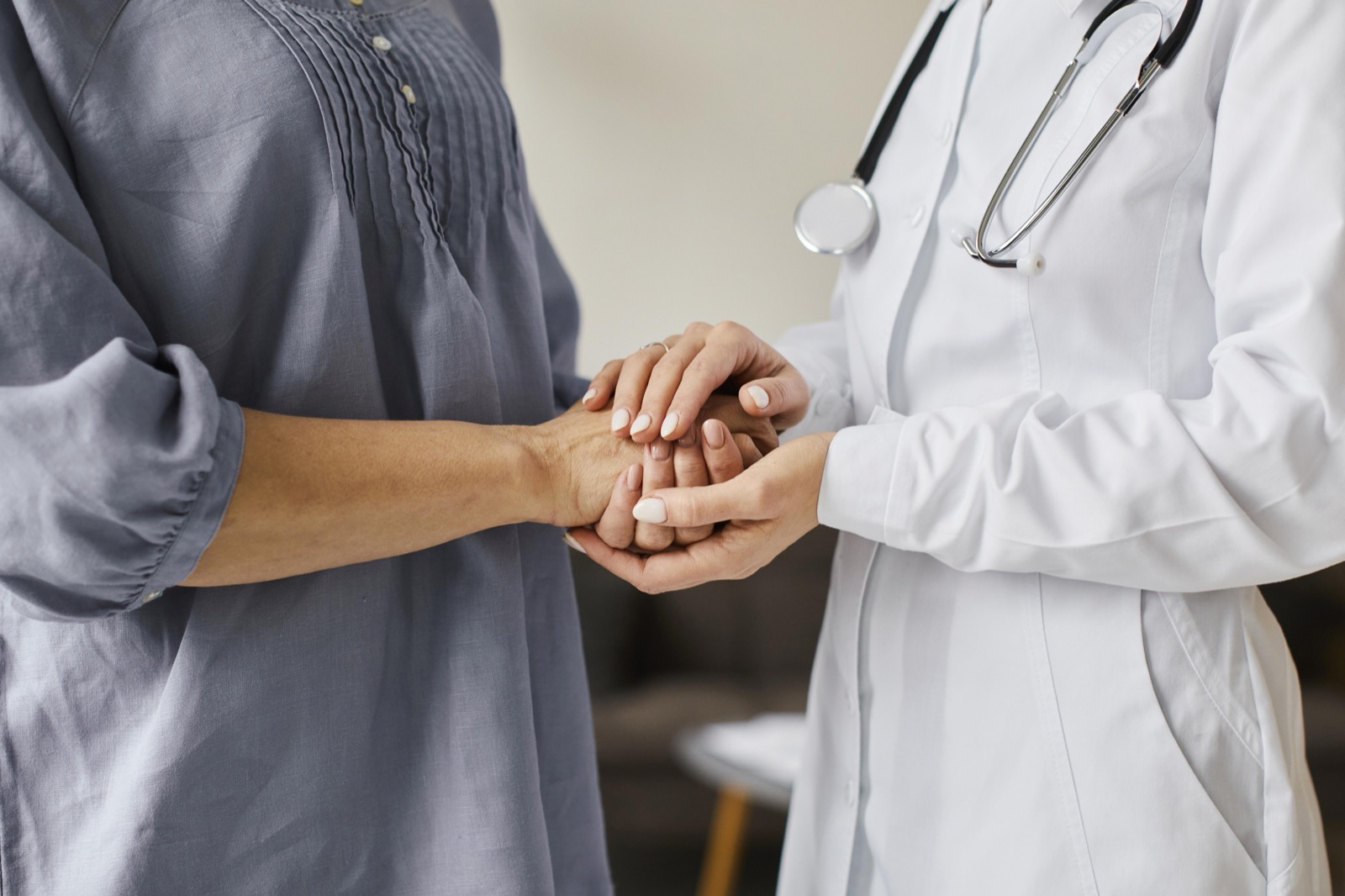 A doctor holding an older patient's hands with both of hers.